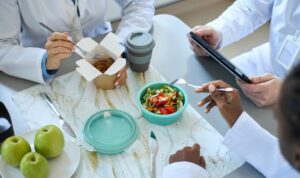 Healthcare professionals eating lunch during a break at a shared table.