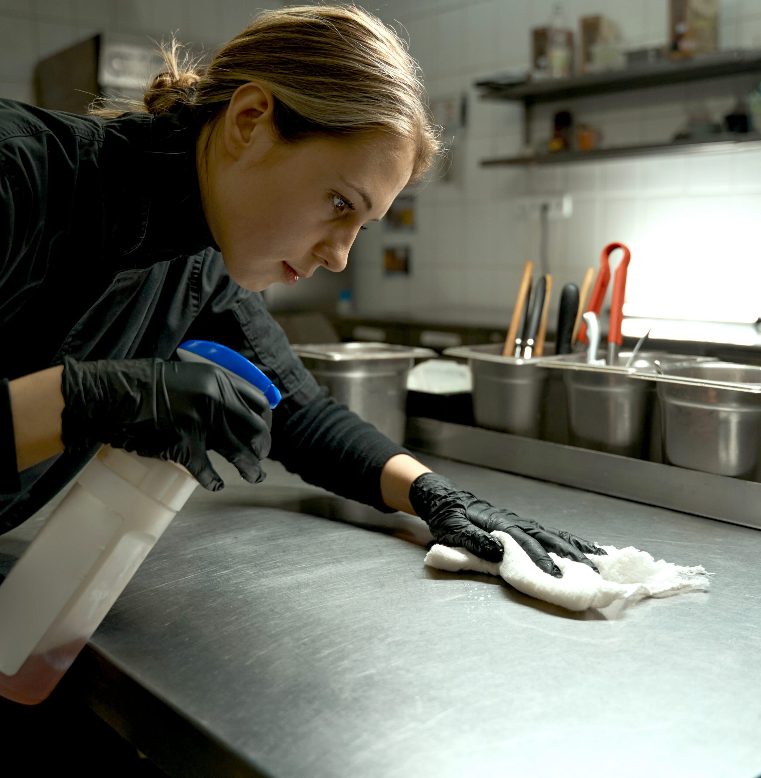 Restaurant chef sanitizes kitchen surfaces.